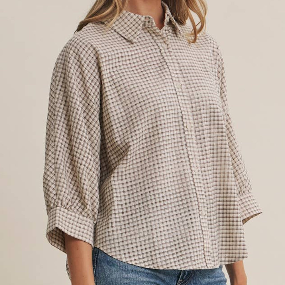 Woman wearing a beige and brown micro-grid plaid button-down shirt with 3/4 length cuffed dolman sleeves.