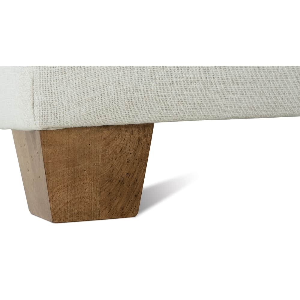 Close-up of the Moreau slipcovered sofa base featuring a light beige fabric and a tapered wooden leg.