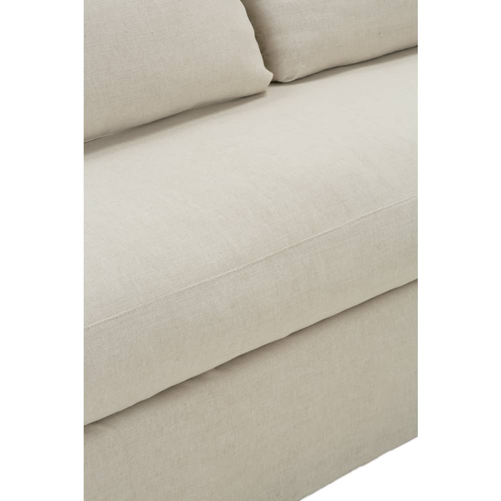 Close-up of the textured beige linen fabric on a slipcovered sofa seat cushion.