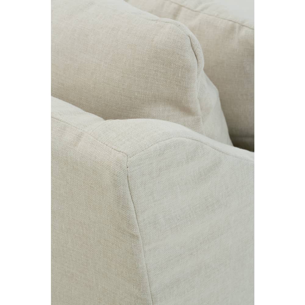 Close-up of a Moreau beige linen slipcovered sofa showing fabric texture, armrest, and plush back cushions.