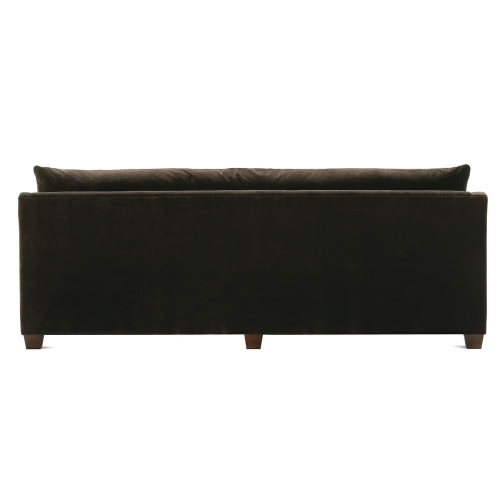 Rear view of a modern brown velvet sofa with wood legs on a white background.