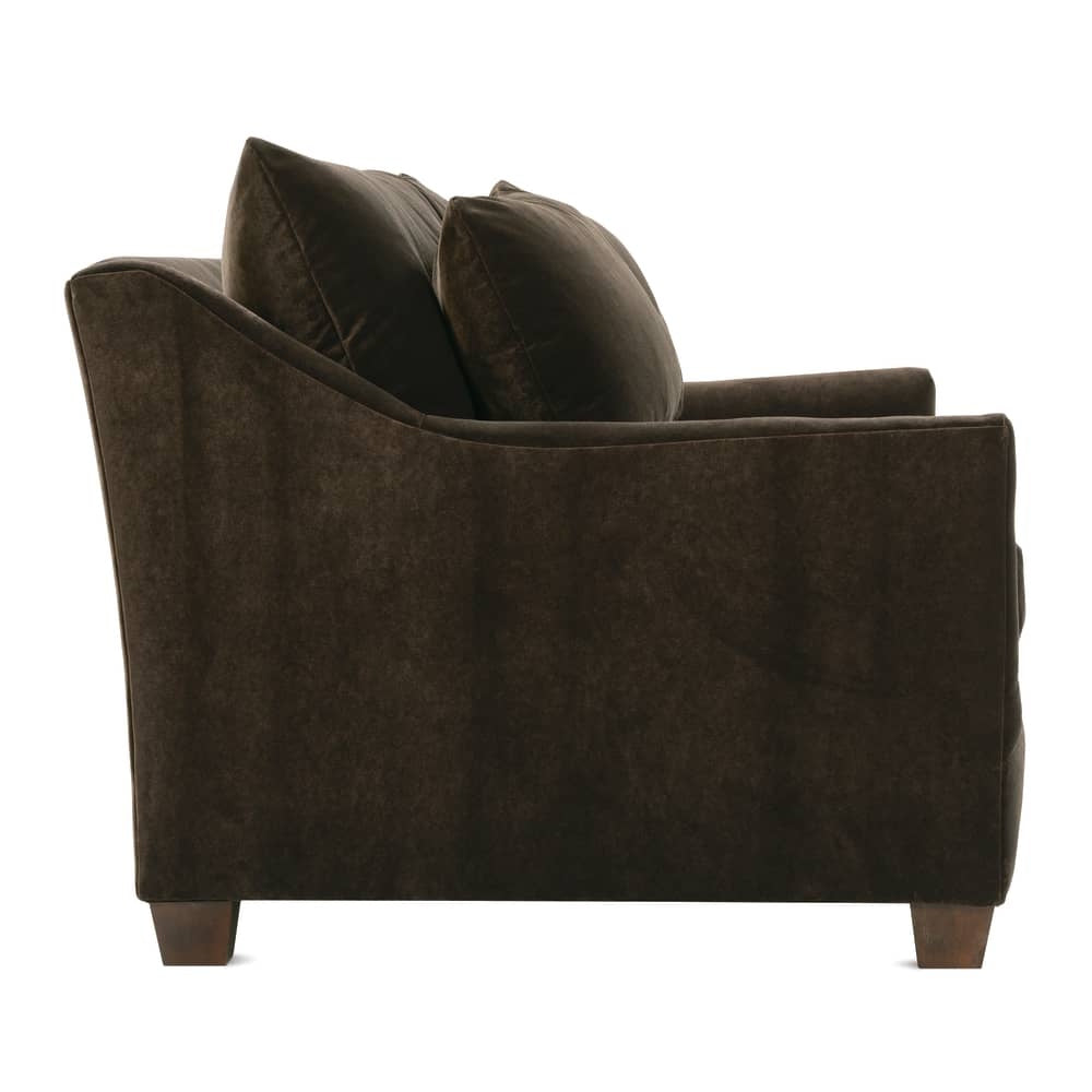 Side profile of a brown velvet sofa with sloped arms and plush back cushions.
