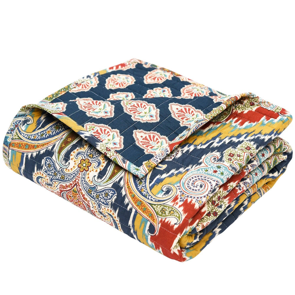 Folded Moreno quilted throw featuring a vibrant blue, yellow, and red paisley and ikat pattern on a white background.