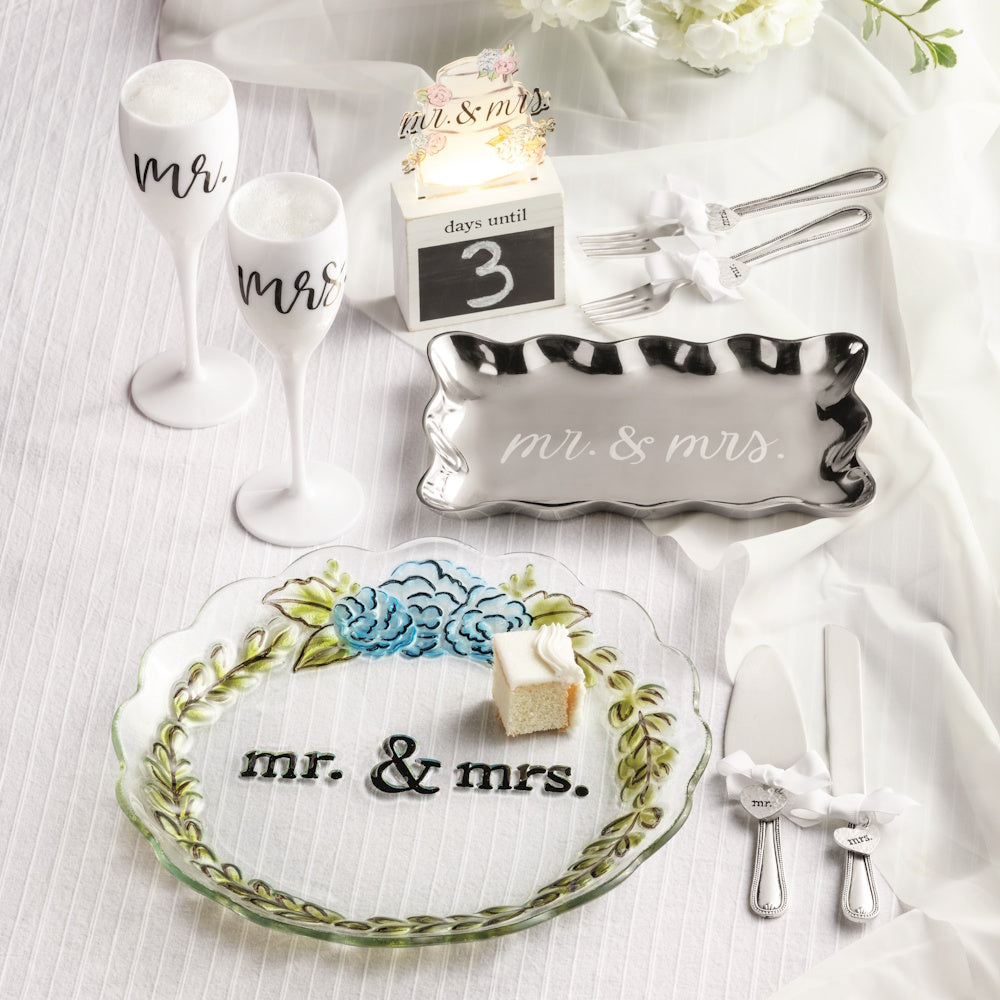A wedding cake server set with "Mr. & Mrs." plates, champagne flutes, forks, and a countdown block.