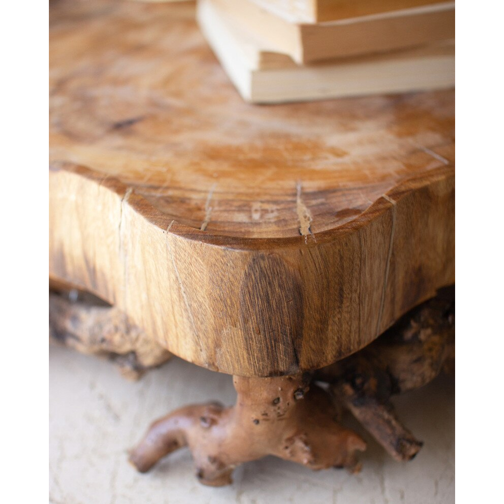 Close-up of a natural wood slab serving tray displaying rich wood grain and a gnarled root leg.