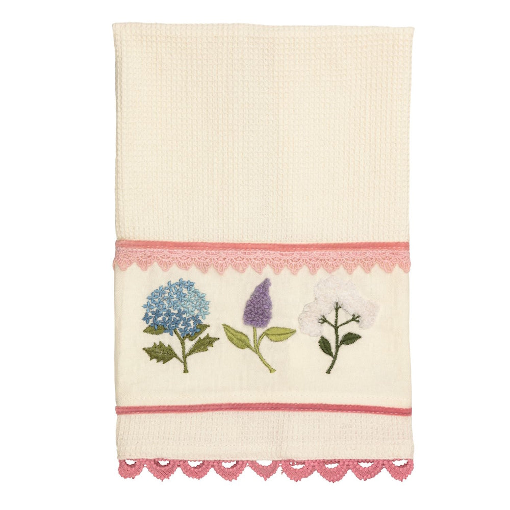 Cream waffle knit hand towel featuring embroidered blue, purple, and white flowers with pink lace trim and scalloped edges.