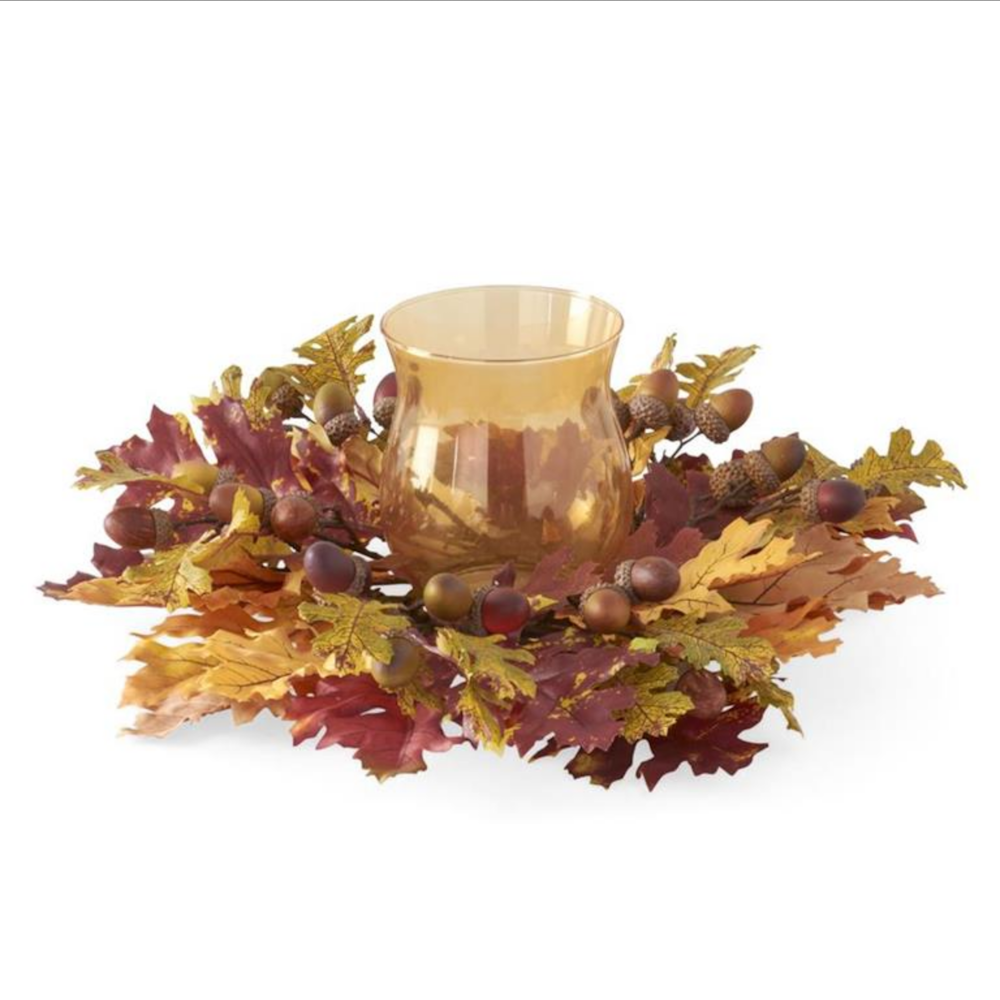 Amber glass hurricane candle holder centered in an autumn wreath of colorful oak leaves and acorns.
