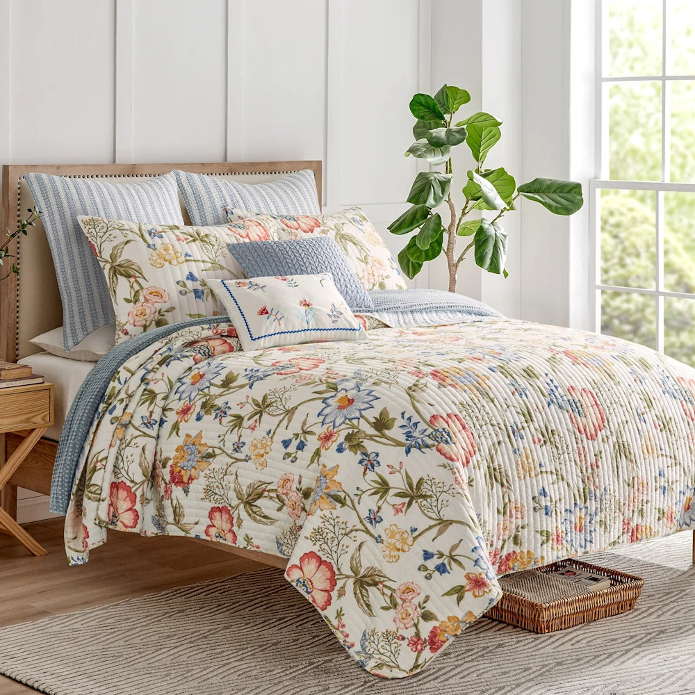 Bed styled with a colorful floral quilt, matching pillow shams, and blue decorative accent pillows.