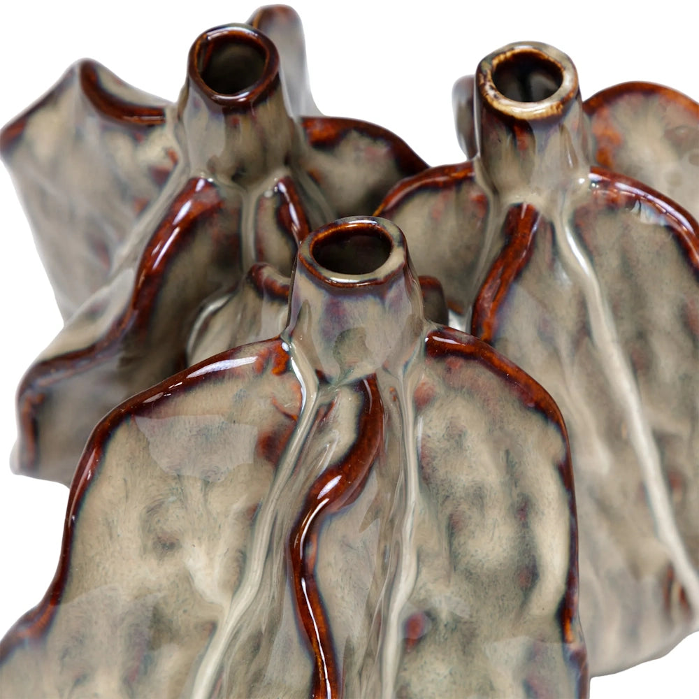 Close-up of a multi-spouted ceramic vase with wavy, leaf-like textures and a glossy brown and grey glaze.
