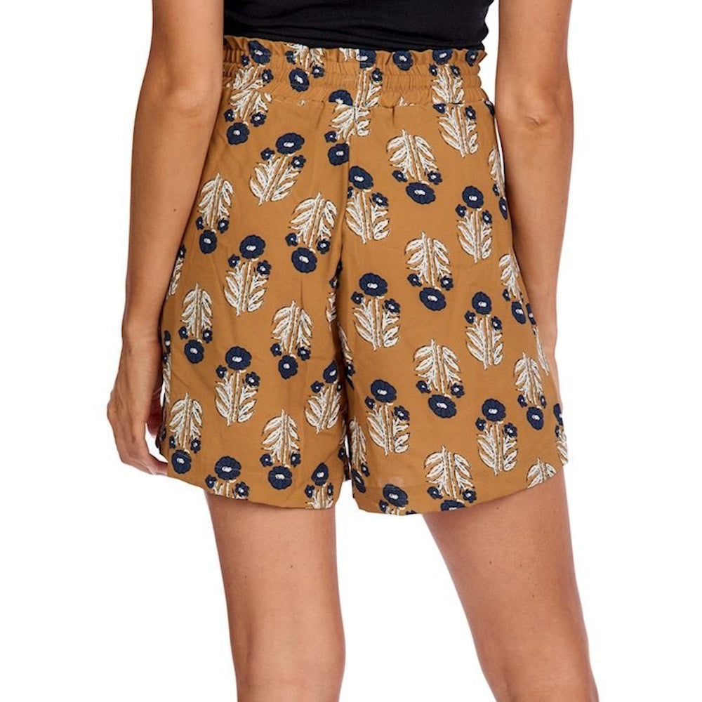 Rear view of a person wearing mustard yellow shorts with a blue and white floral pattern and a paperbag waist.