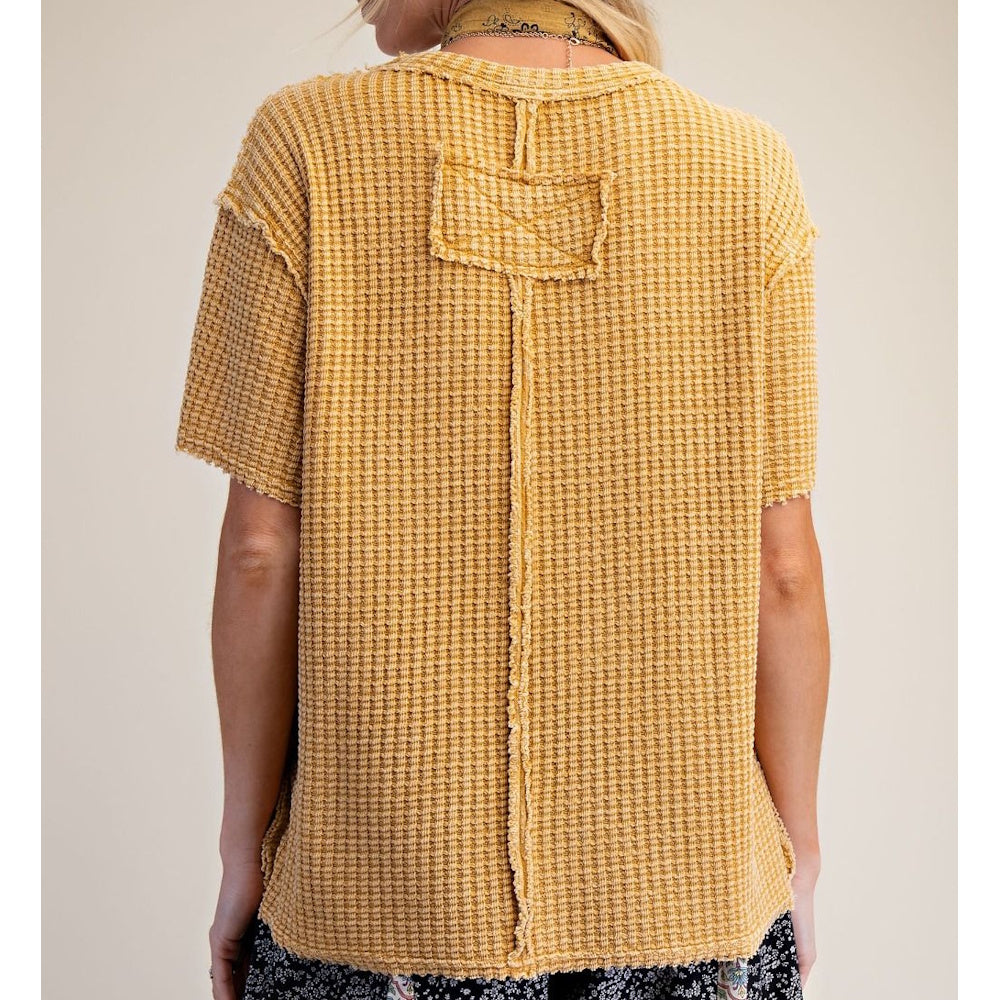 Back view of a yellow mustard waffle knit short-sleeve top with raw edge seams and a patch detail.