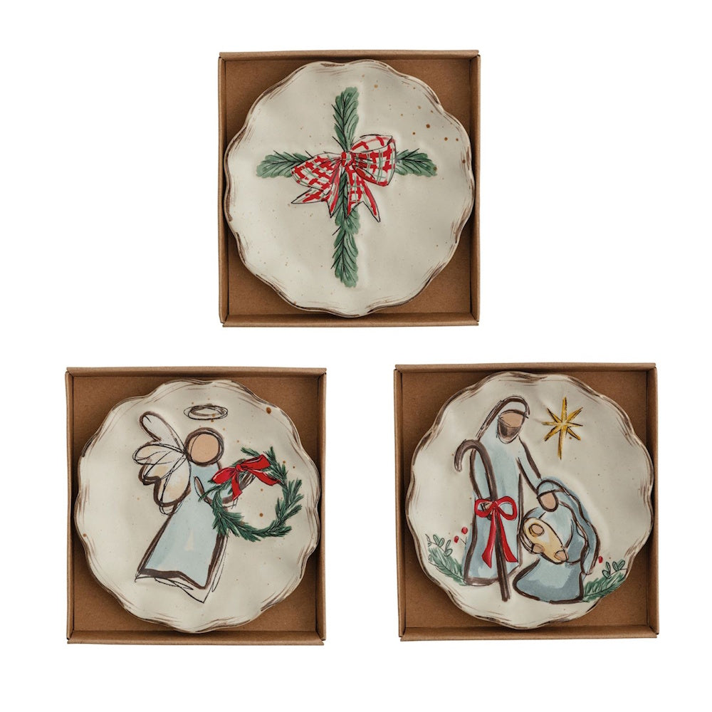 Set of three ceramic holiday tidbit plates in gift boxes featuring greenery, an angel, and a nativity scene.