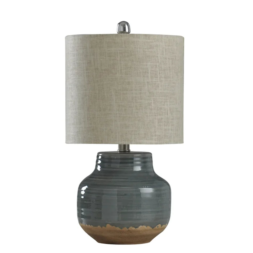 Rustic gray ceramic table lamp with a textured linen drum shade and natural clay base accent for home decor.