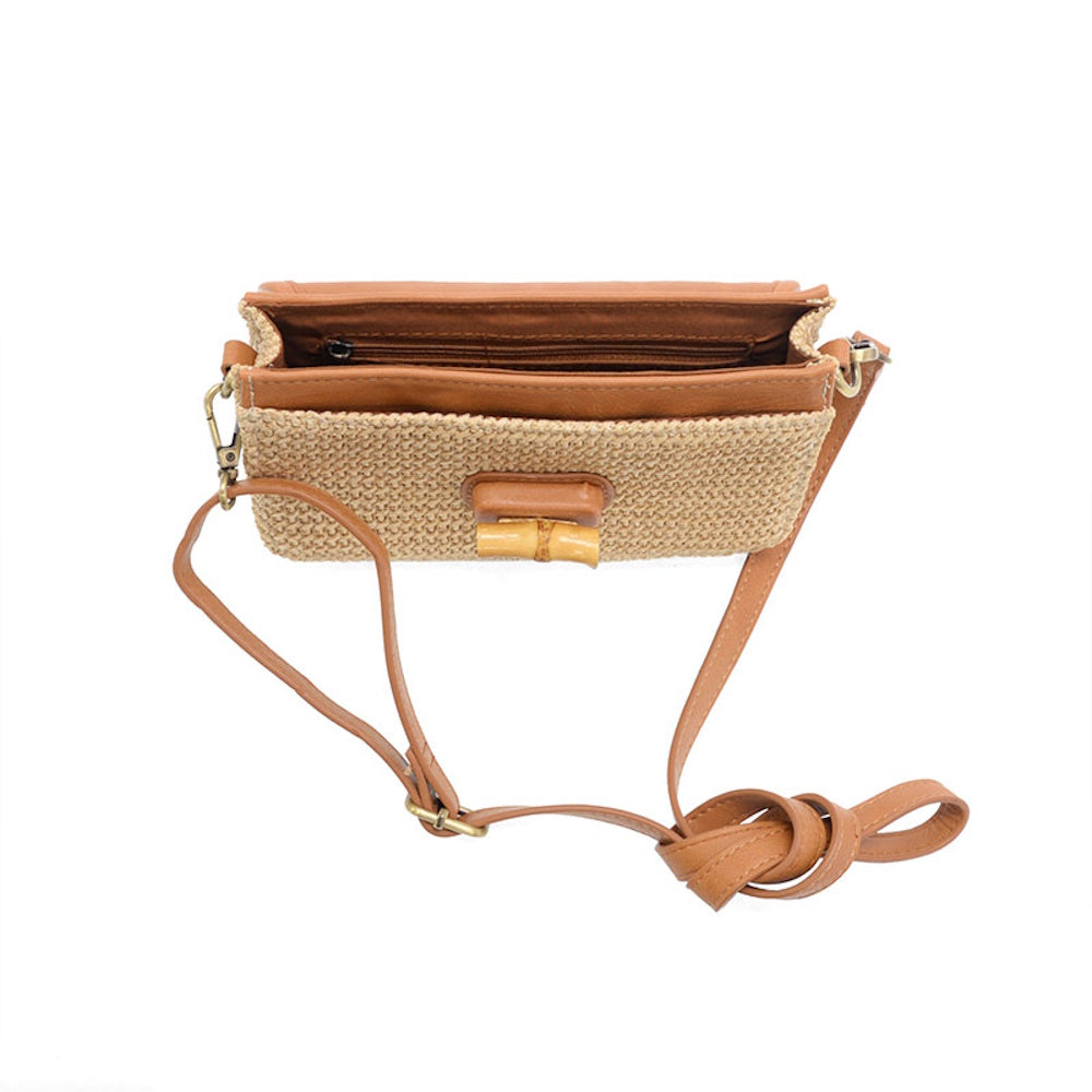 Top view of an open straw crossbody bag with tan leather trim, bamboo turnlock, and organized interior compartments.