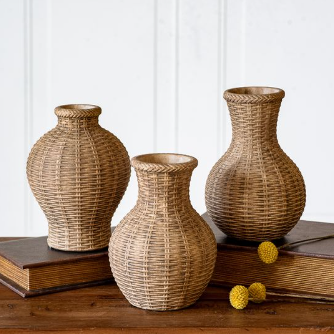 Set of three beige woven textured stoneware vases in assorted shapes displayed on vintage books.
