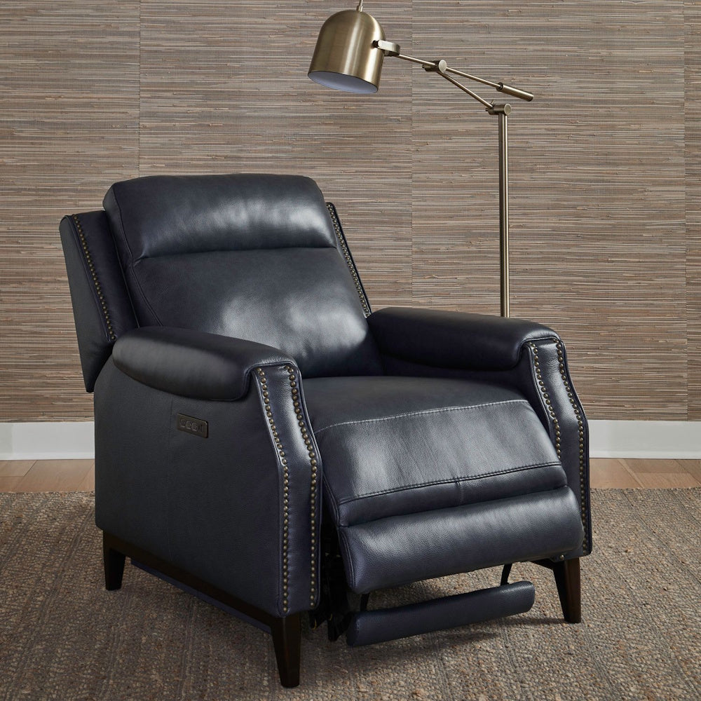 Modern navy blue leather power recliner chair with brass nailhead trim and a brass floor lamp in a living room setting.