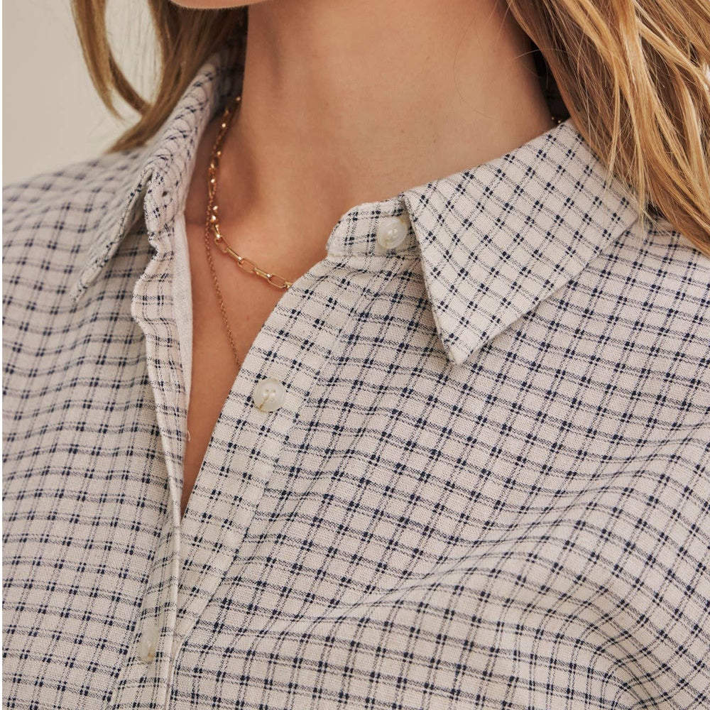 Close-up of a person wearing a white button-down shirt featuring a fine navy micro-grid plaid pattern.
