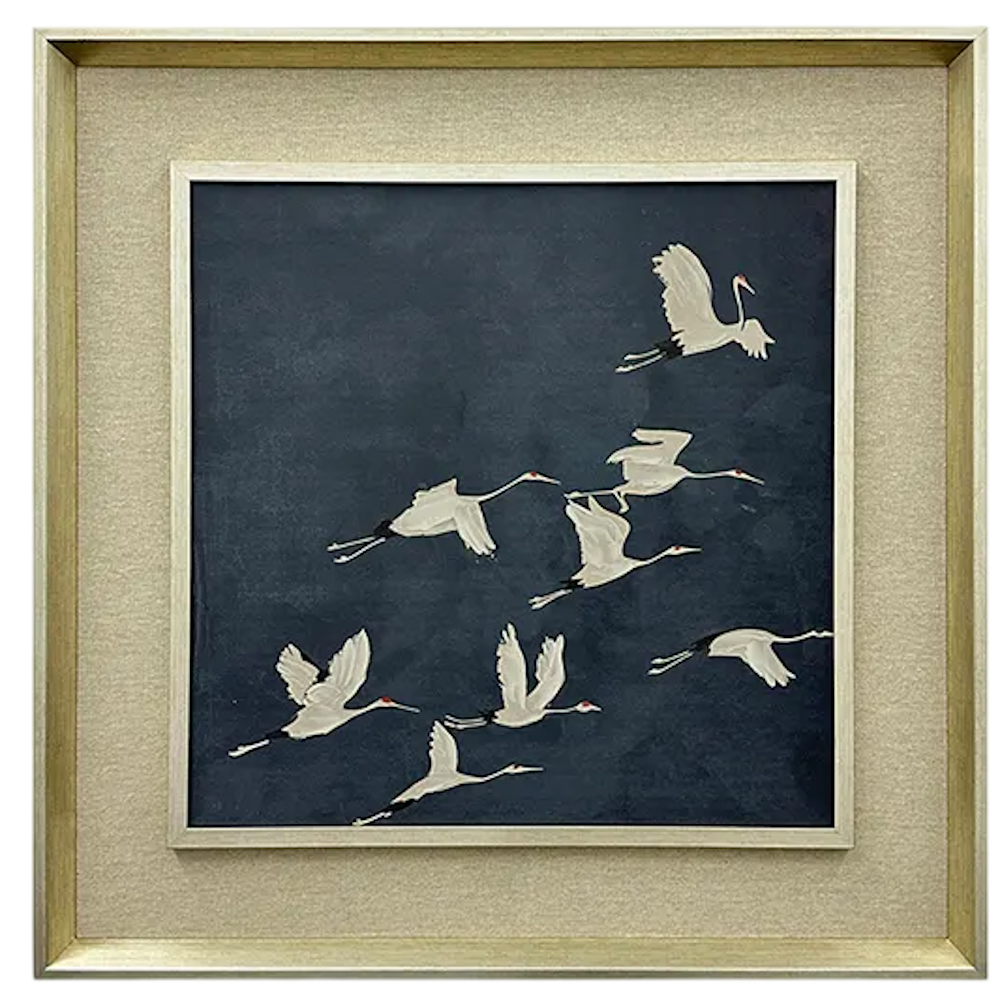 Framed wall art featuring white cranes flying across a dark navy blue background set in a light metallic frame.