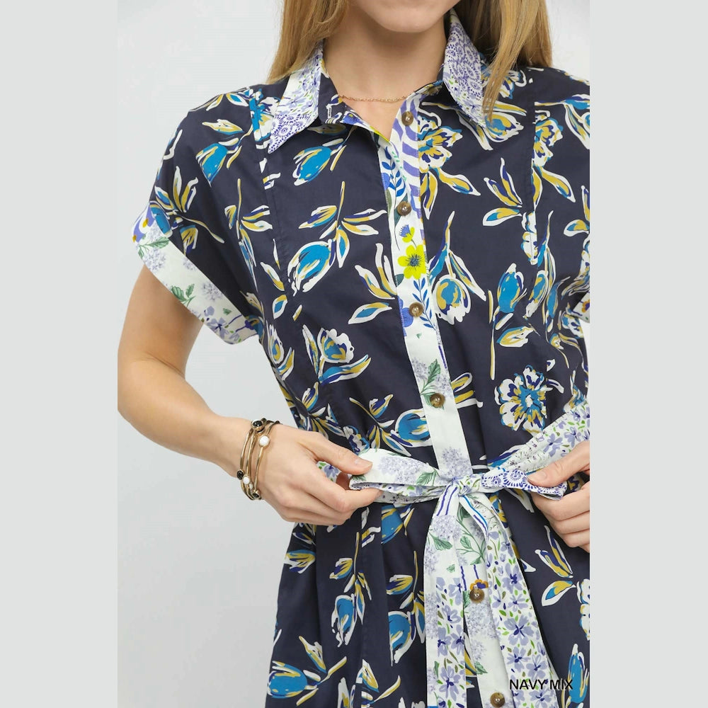Close-up of a navy floral button-front midi dress featuring a contrast print tie belt and collar.