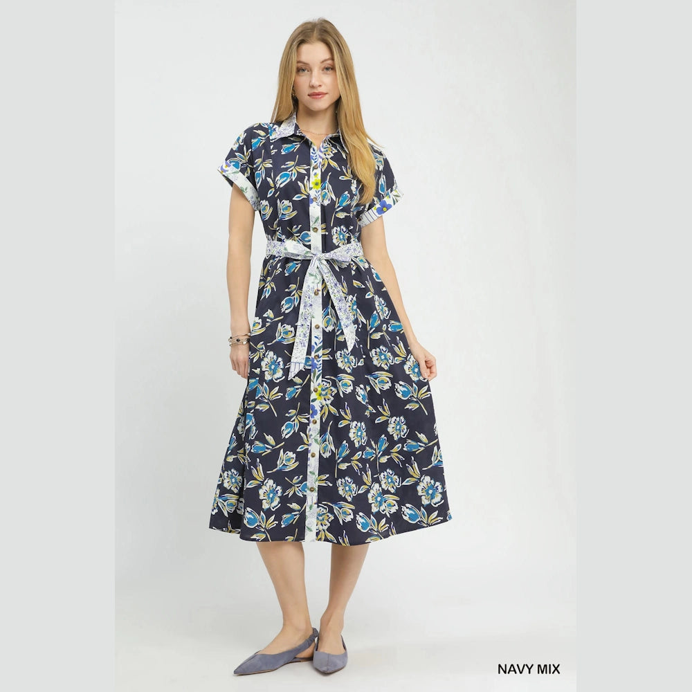 Navy floral button-front midi dress with short sleeves, a patterned tie belt, and blue flats against a white background.
