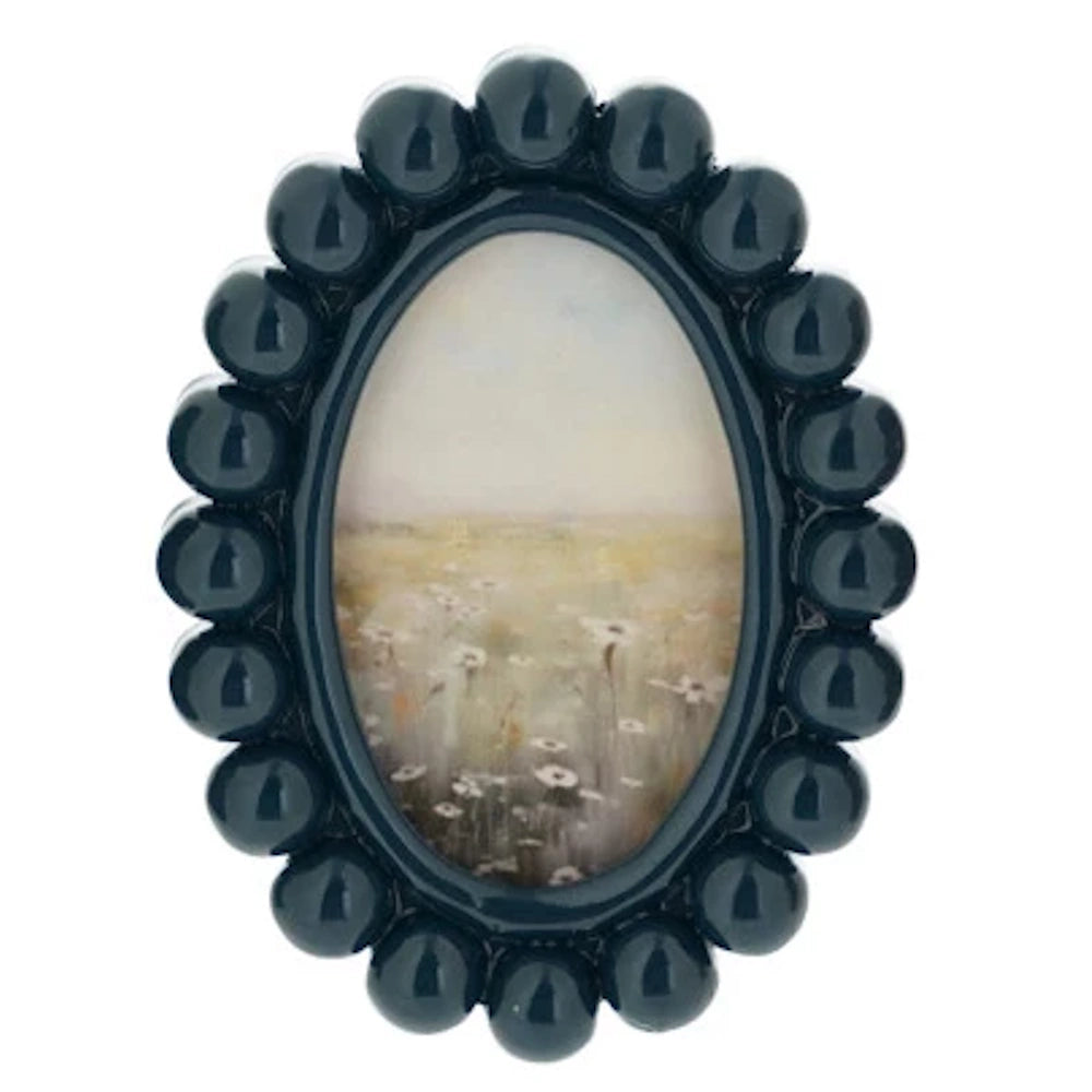 Navy blue oval resin bobbin photo frame featuring a landscape painting of a wildflower meadow with white daisies.