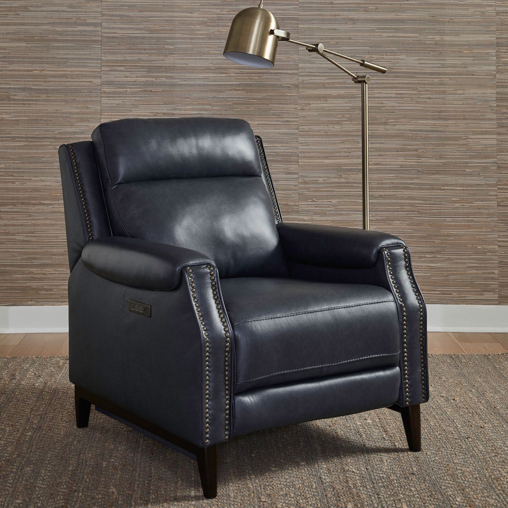 Modern navy blue leather power recliner with brass nailhead trim and a gold floor lamp in a living room.