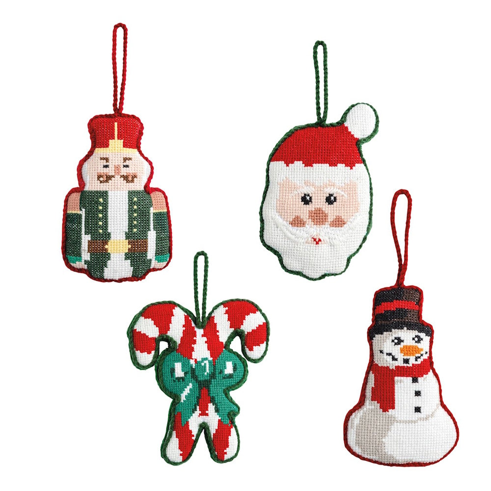 Four needlepoint Christmas ornaments: a nutcracker, Santa, candy canes, and a snowman.