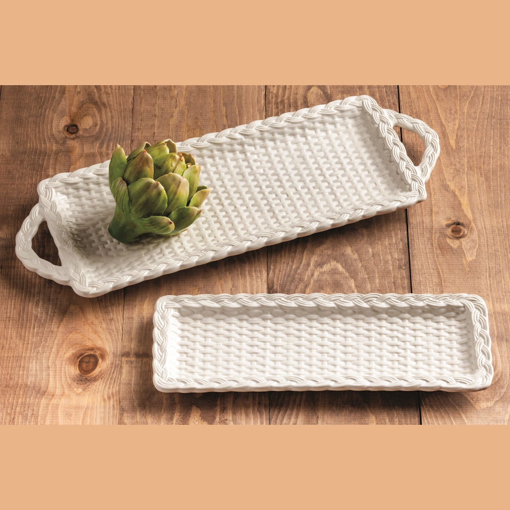 White woven ceramic nesting trays with handles on a wooden table, featuring a decorative artichoke accent.