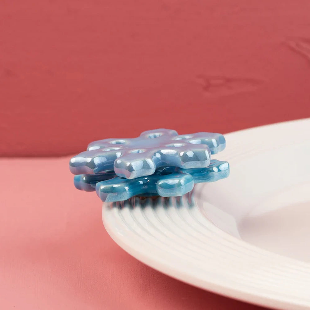 Iridescent blue snowflake platter decoration attached to the rim of a white ceramic plate.