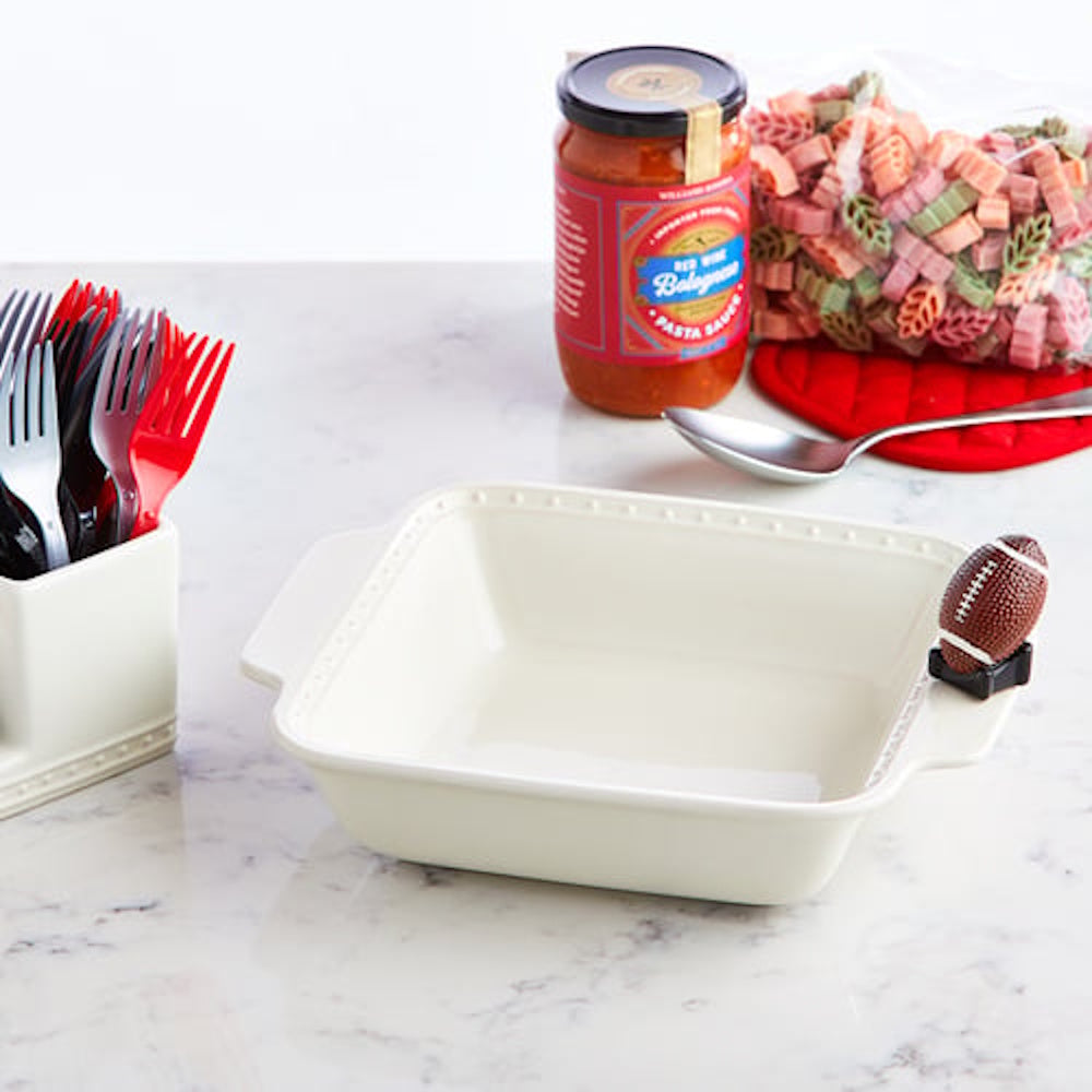 White square ceramic baking dish with a small football figurine attached to the handle.