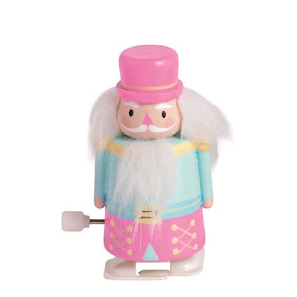 Pastel nutcracker wind-up toy in a pink hat and light blue outfit on a plain white background.