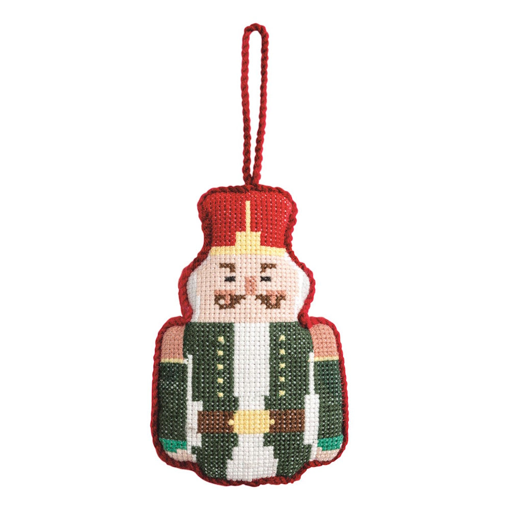 Hand-stitched needlepoint nutcracker Christmas ornament with a red hat, green jacket, and hanging loop.