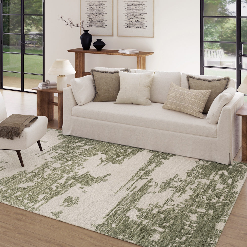 Modern abstract hand-tufted green and ivory area rug in a minimalist living room with a white sofa and wooden furniture.