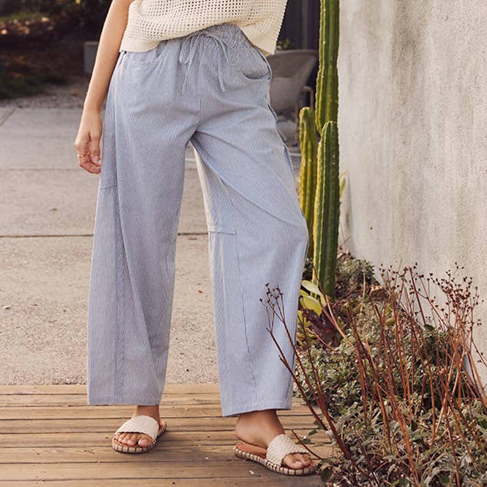 Relaxed blue-and-white striped barrel pants with a drawstring waist, paired with sandals outdoors.