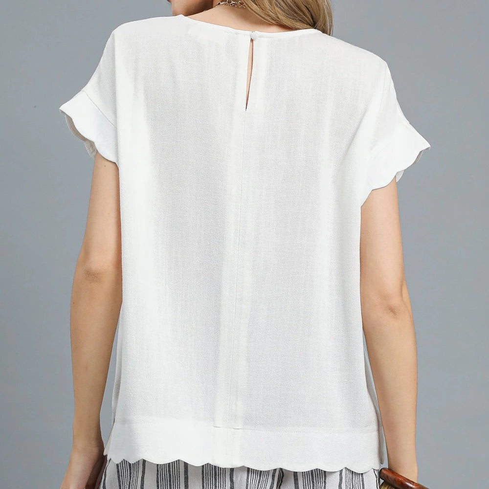 Back view of a white, short-sleeved blouse with a scalloped hem and keyhole closure against a gray background.