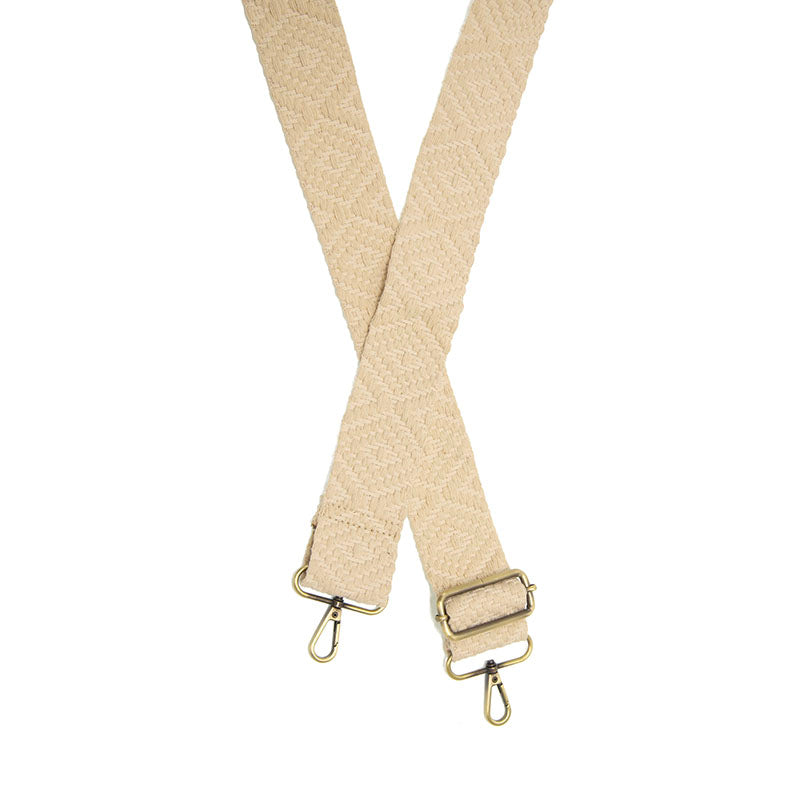 Off-white woven guitar strap with a geometric diamond pattern and brass-colored swivel lobster clasps.