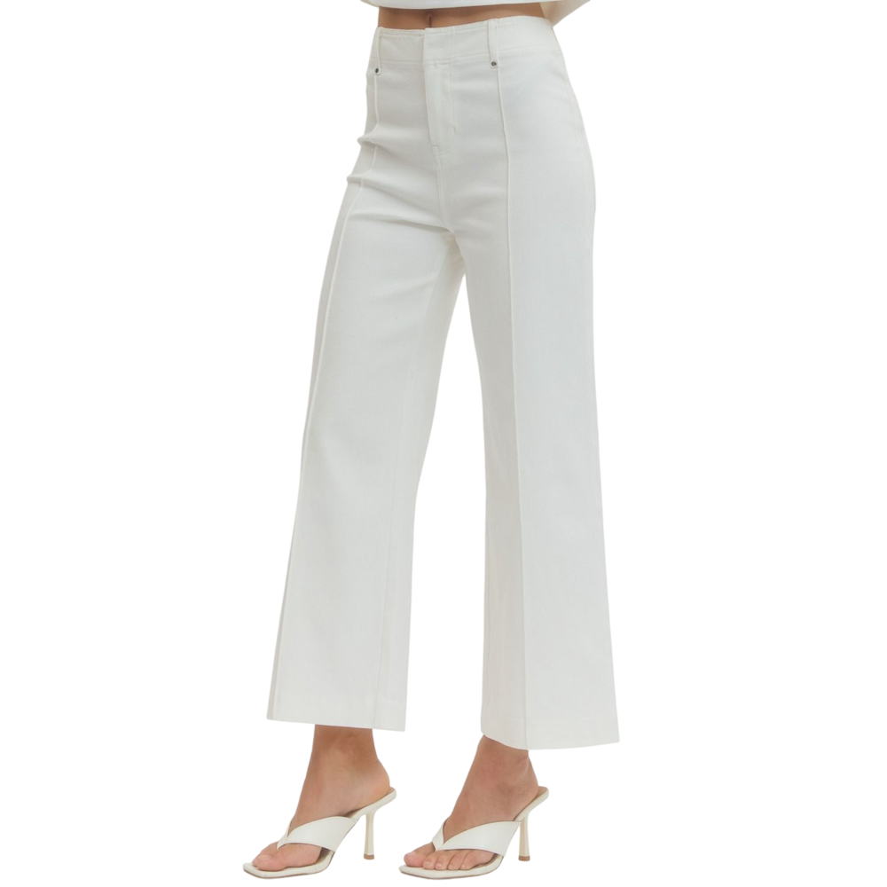 A person wearing off-white, high-rise, wide-leg pants with front seams and white heeled sandals.