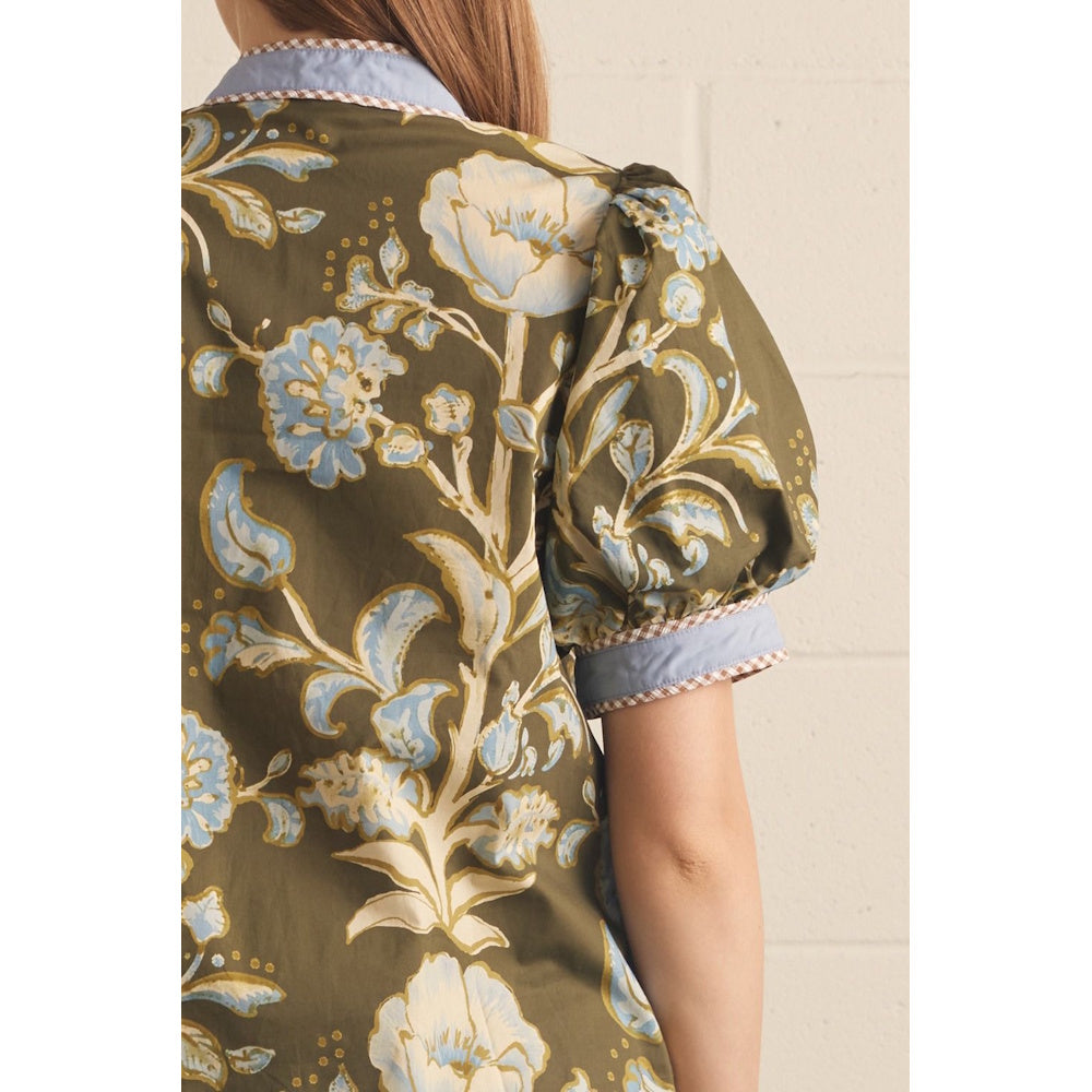 Back view close-up of an olive green top featuring blue floral print, puff sleeve, and patterned trim.
