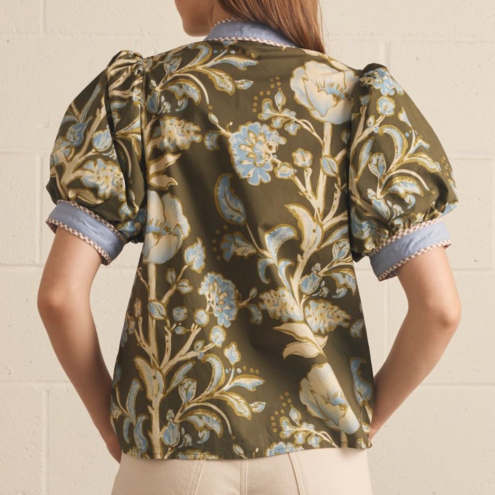 Back view of an olive green top featuring a light blue floral pattern and cuffed puff sleeves.
