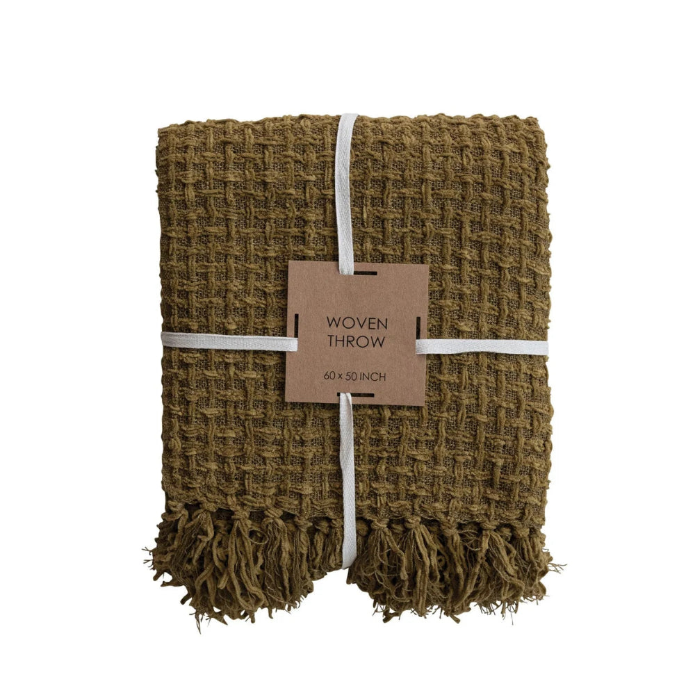 Folded olive green waffle-weave woven throw blanket with fringed edges and product tag.