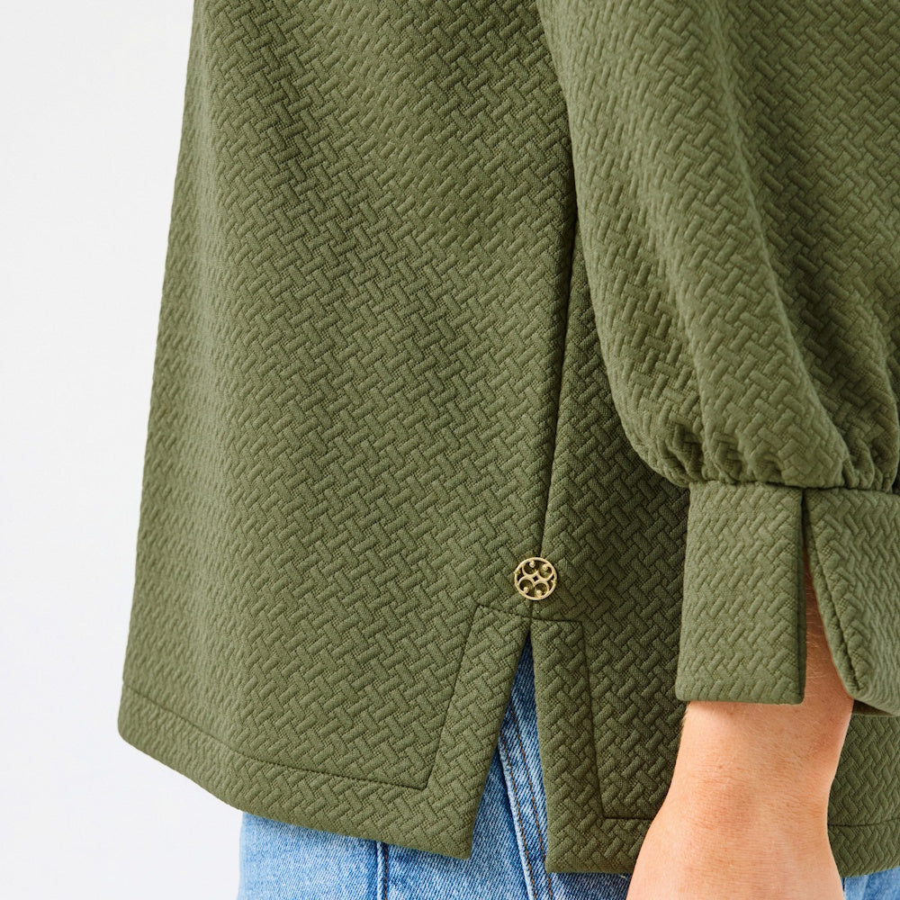 Close-up side view of the olive green textured blouse showing the side slit and gold button detail.