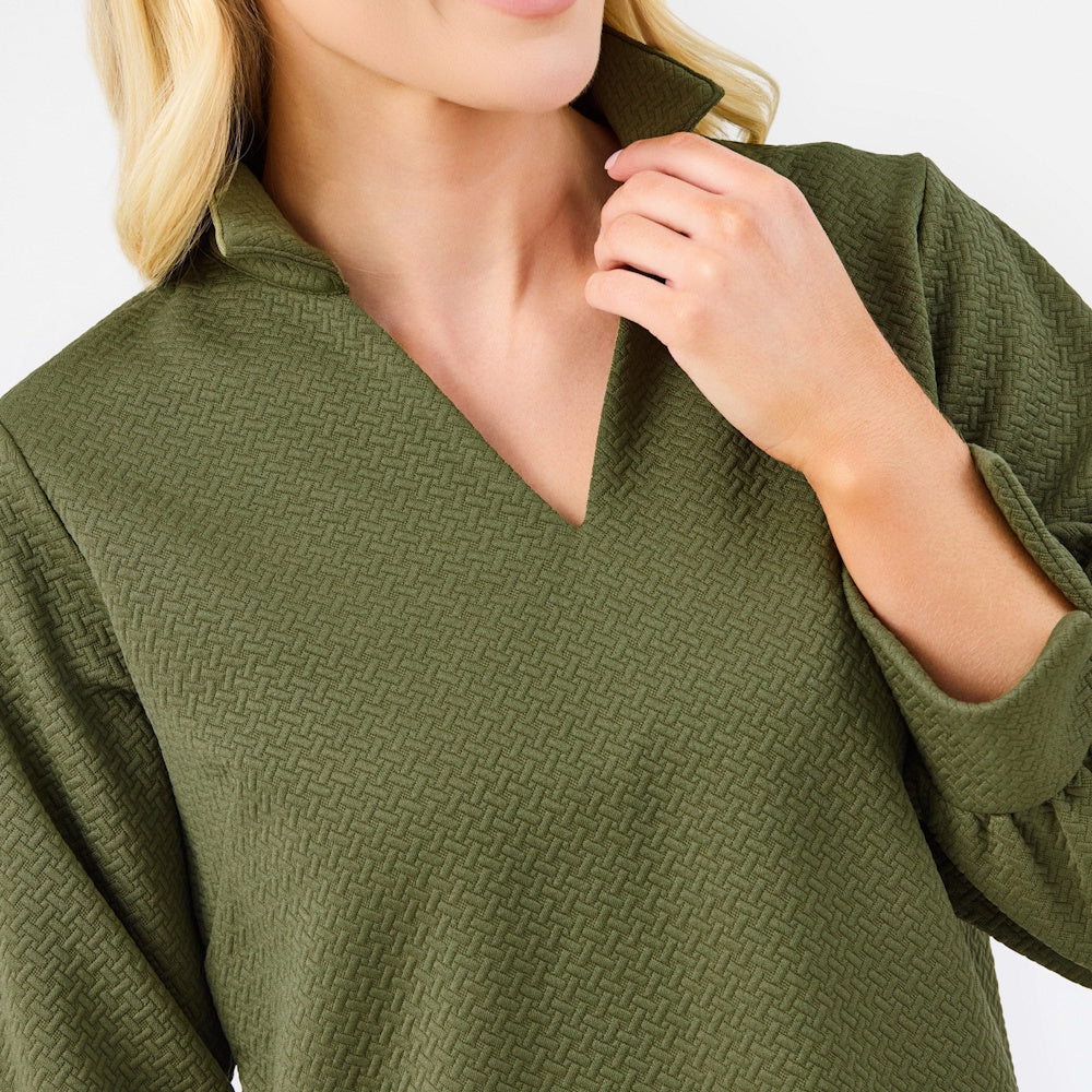 Close-up of the olive green textured blouse neckline and V-neck collar detail.