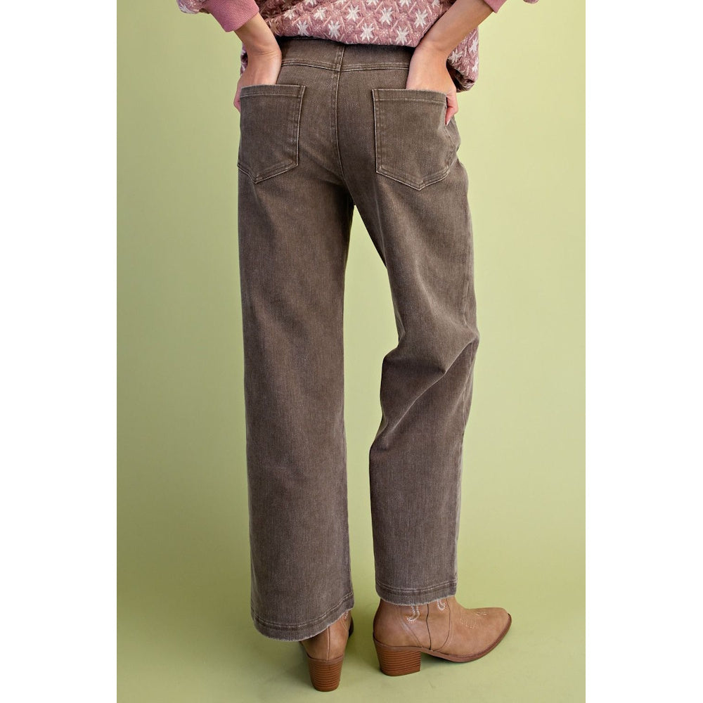Back view of olive green washed wide-leg twill pants with back patch pockets and tan boots.