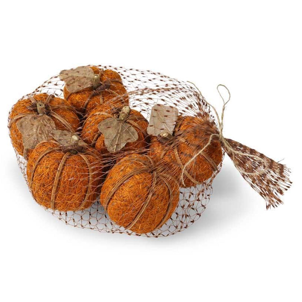 A mesh bag filled with six textured, orange decorative pumpkins made of natural fibers on a white background.