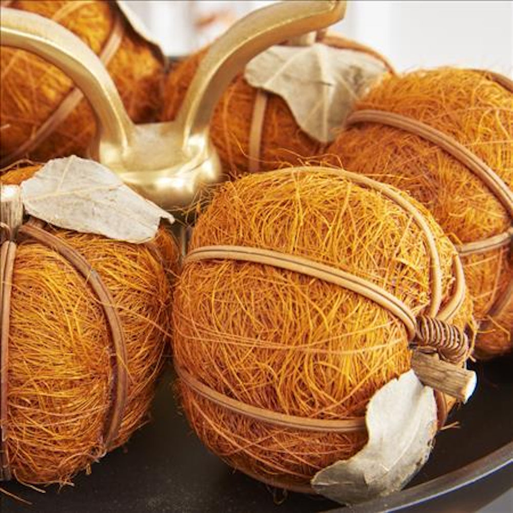 Decorative pumpkins crafted from textured orange fiber husks with wooden stems and pale leaves.