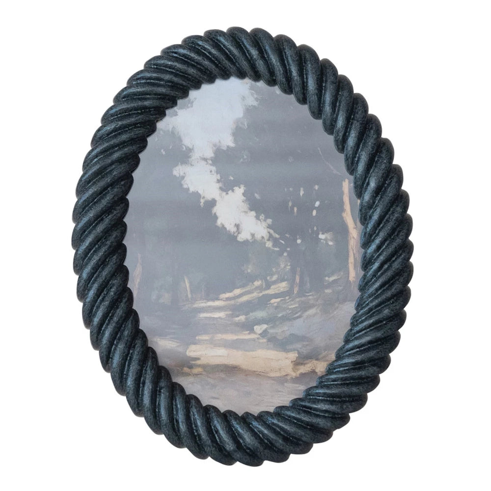 Oval black resin picture frame with a twisted rope design featuring a landscape painting of a sunlit forest path.