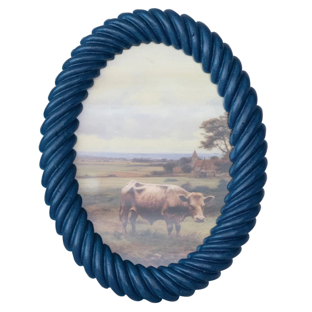 Navy blue oval resin photo frame with a twisted rope border featuring a vintage landscape painting of a cow in a field.