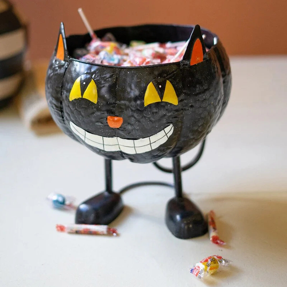 A painted metal black cat Halloween candy bowl with legs, filled with colorful lollipops.