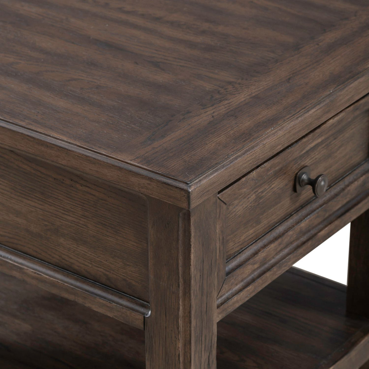Close up of dark wood end table corner featuring framed drawer front, round knob and rich wood grain detail.