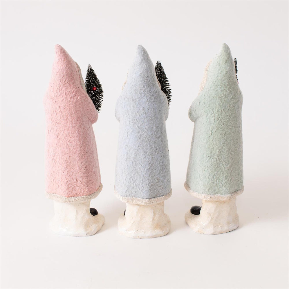 Back view of three pastel Belsnickel Santa figurines in pink, blue, and green holding trees.